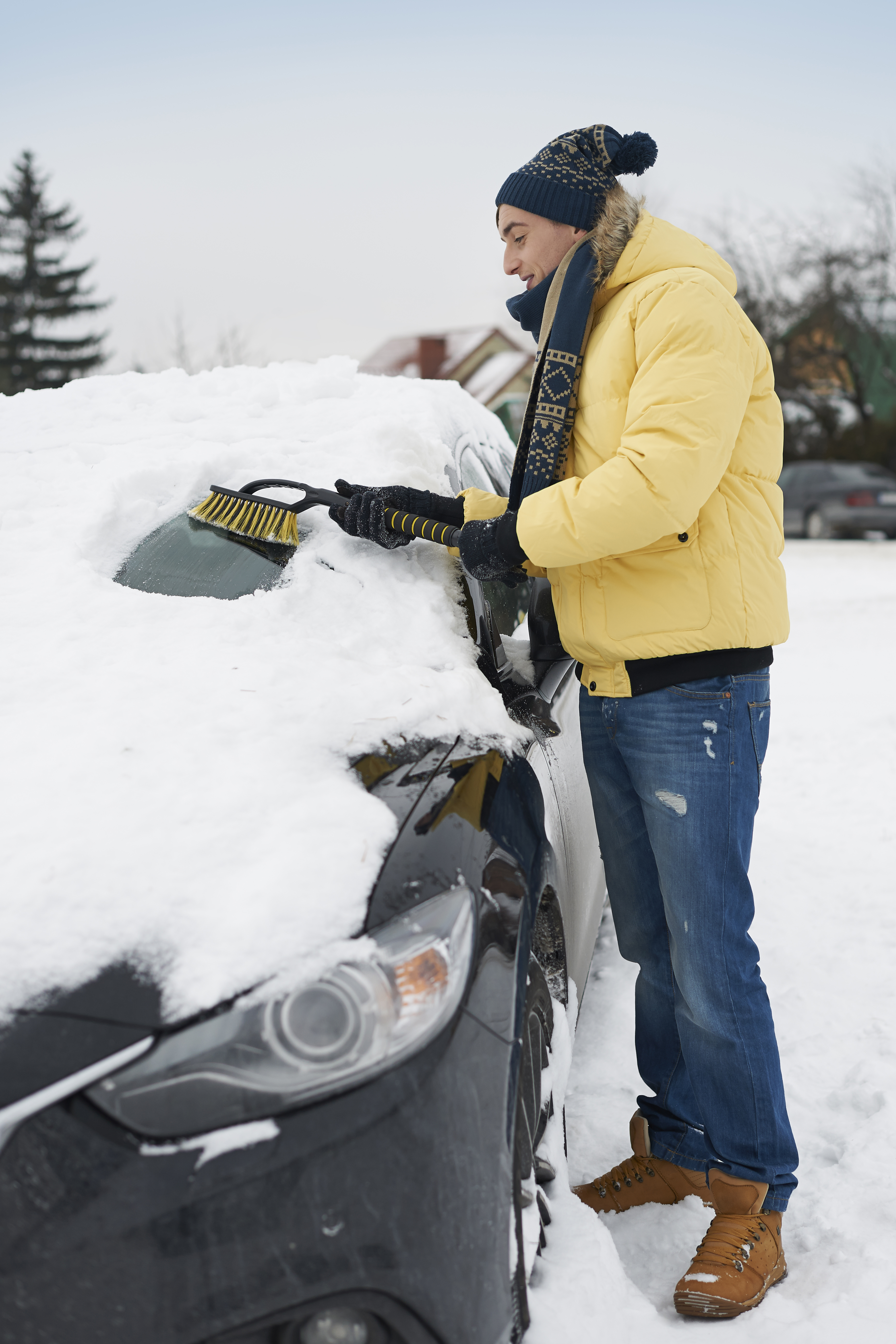 Professional clearing snow and ice from vehicle and parking area